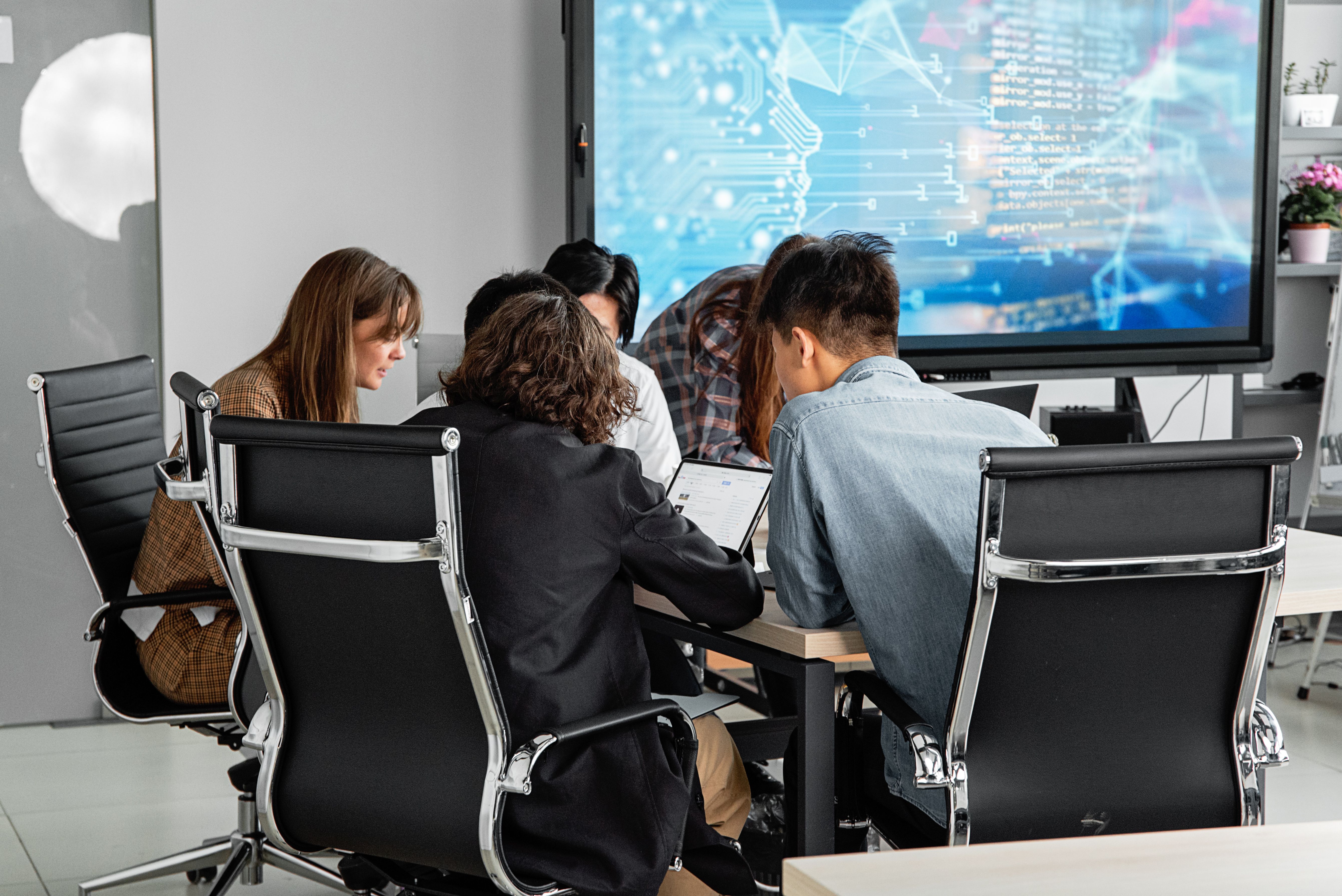 Equipo de trabajo en reunión frente a pantalla con datos